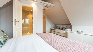 Ein Schlafzimmer mit Bett, einer Couch, einem kleinen Tisch und einer Tür zu einem Badezimmer.