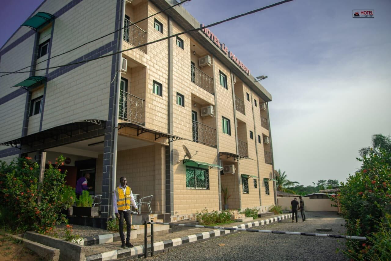 A multi-story hotel with a brick facade, balconies, and a covered entrance.