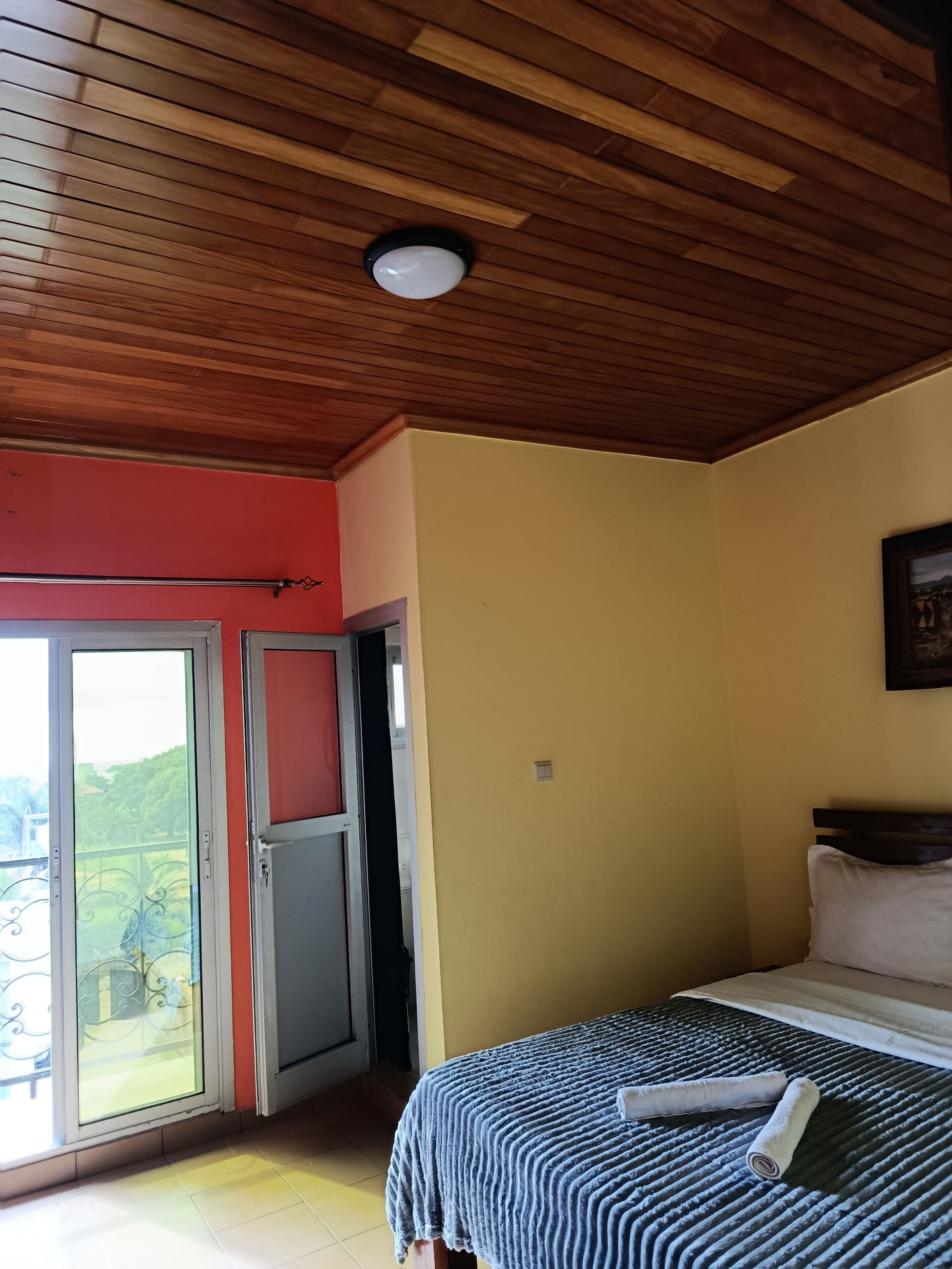 Quarto com uma cama, janela e porta que dá para uma varanda.