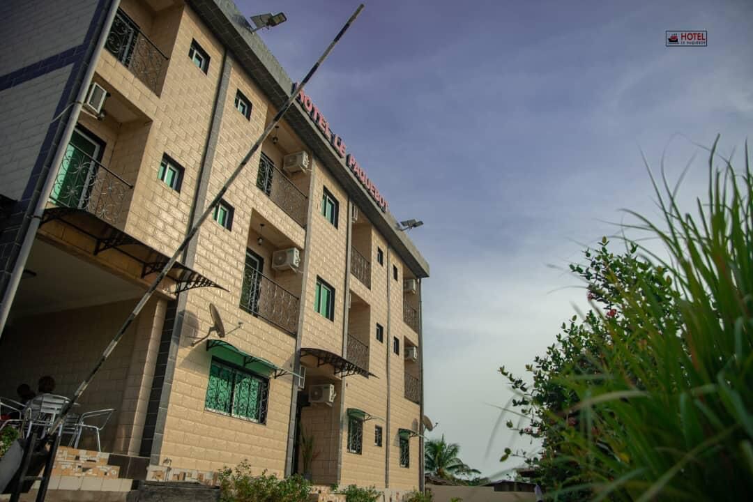 A multi-story hotel building with balconies, satellite dishes, and a sign indicating it is a hotel.