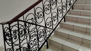 A staircase with ornate black metal railings and white tiled steps.
