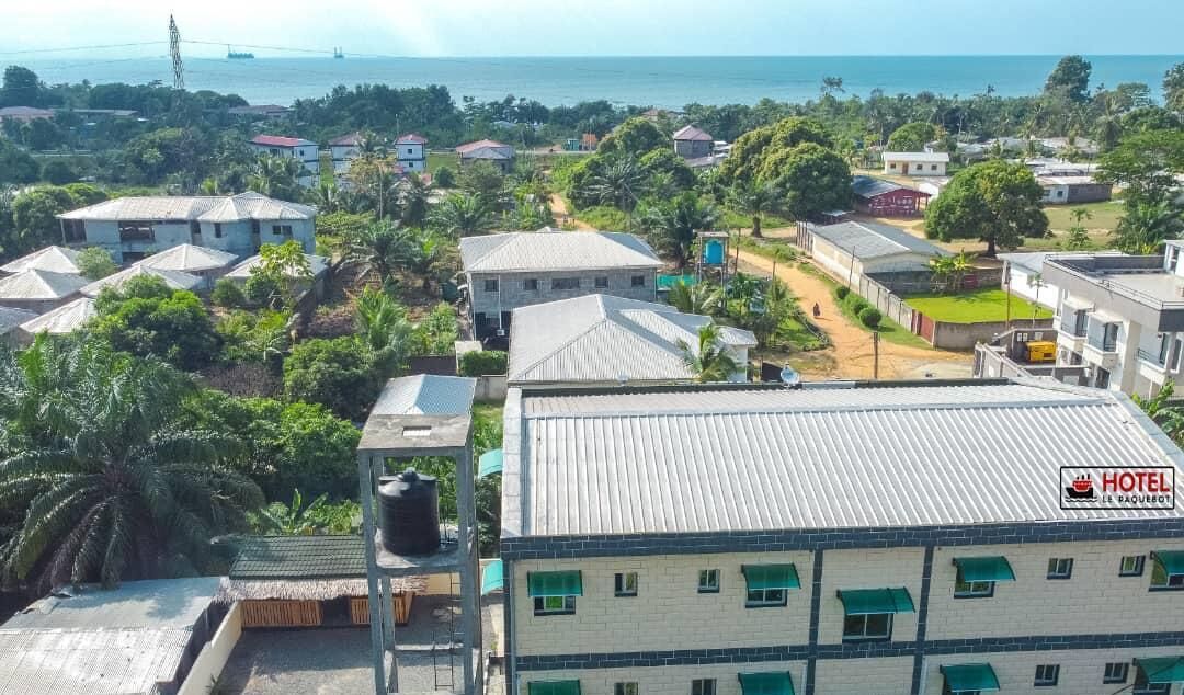A hotel with multiple buildings, a view of the sea, and surrounding greenery.