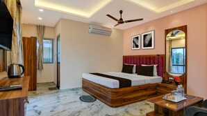Una habitación de hotel moderna con cama, escritorio, silla, ventilador de techo, unidad de aire acondicionado y espejo.