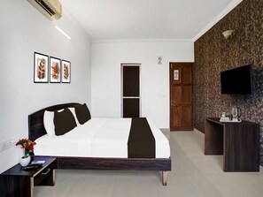 Ein Hotelzimmer mit Bett, Schreibtisch, Fernseher und Bildern an der Wand.