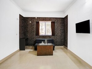 A room with a sofa, a coffee table, a TV mounted on the wall, and a window with curtains. - Deluxe Hotel Springs (Alto de Porvorim)