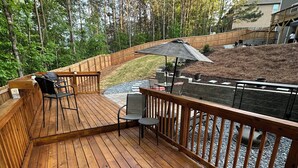 A wooden deck with outdoor furniture, a stone pathway, and a view of a wooded area. - Backyard event space with basement apartment with kitchen, fitness room. (Fairburn)