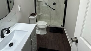 A bathroom with a white sink, a toilet, a shower enclosure, and a mirror. - Backyard event space with basement apartment with kitchen, fitness room. (Fairburn)