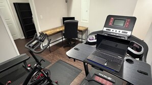 A home gym with a treadmill, stationary bike, and a weight bench. - Backyard event space with basement apartment with kitchen, fitness room. (Fairburn)