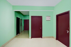 A hallway with green walls, a tiled floor, and closed doors.
