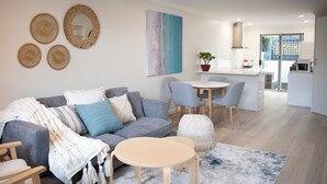 A modern living room with a grey sofa, round coffee table, and a dining area with a small table and chairs. - Family Friendly Coastal Oasis (Scarborough)