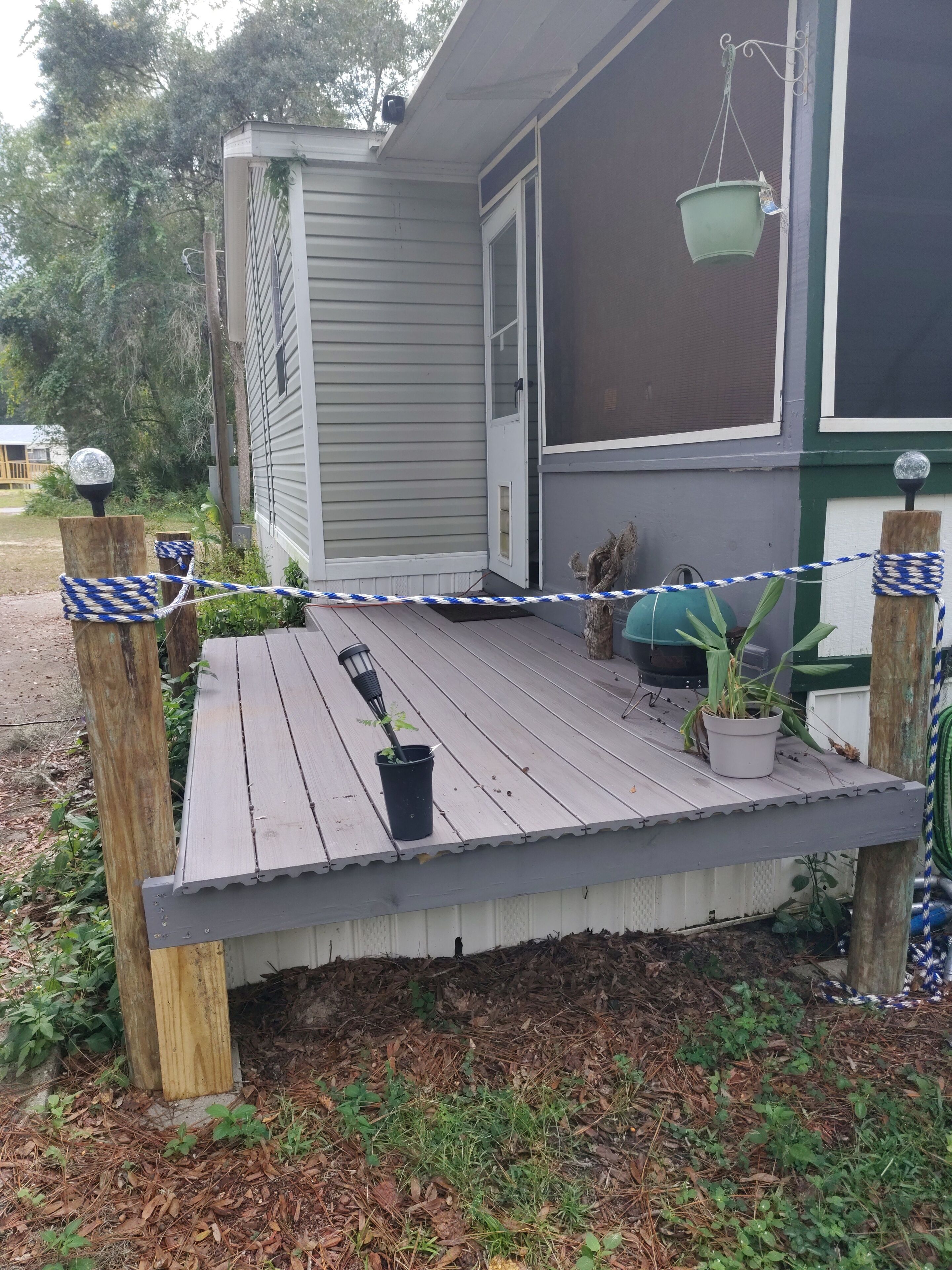 A covered porch with a wooden bench, potted plants, and a hanging planter.