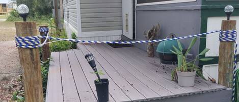A covered porch with a wooden bench, potted plants, and a hanging planter.