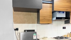 A modern kitchen with a stainless steel refrigerator, a wooden countertop, and a built-in stove. - Constatia Homes (Kampala)