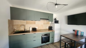 Eine moderne Küche mit türkisfarbenen Schränken, einem eingebauten Ofen, einer Mikrowelle und einem Essbereich mit Holztisch und Stühlen.