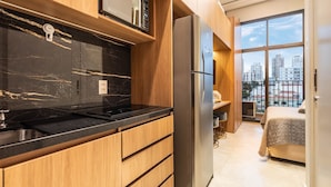 Una cocina moderna con microondas integrado, refrigerador de acero inoxidable y armarios de madera.
