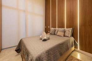 Un lit bien fait, avec une couvre-lit matelassée, une serviette enroulée et des coussins à motifs.
