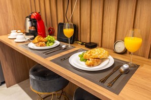 Une table en bois dressée pour le petit-déjeuner, avec des croissants, des raisins et du jus d’orange.