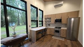 Et moderne køkken med store vinduer, et spiseområde og udsigt til en skov.