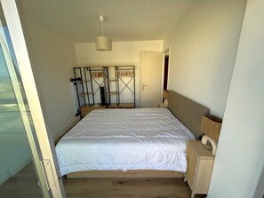 Ein Schlafzimmer mit Bett, Kleiderschrank, Heizkörper und einer Pendelleuchte.