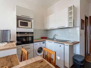 Eine kompakte Küche mit Mikrowelle, Backofen, Geschirrspüler und Waschmaschine.