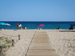 A wooden boardwalk leading to a sandy beach with umbrellas and people. - Ideal studio near the beach - 2 guests (Torredembarra)