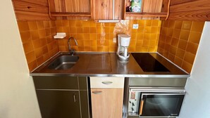 Una cucina compatta con lavandino, macchina da caffè e forno a incasso.