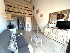 A living room with a sofa, a television, a cabinet, and a staircase. - Apartment near beach with parking - 5 guests (Argelès-sur-Mer)