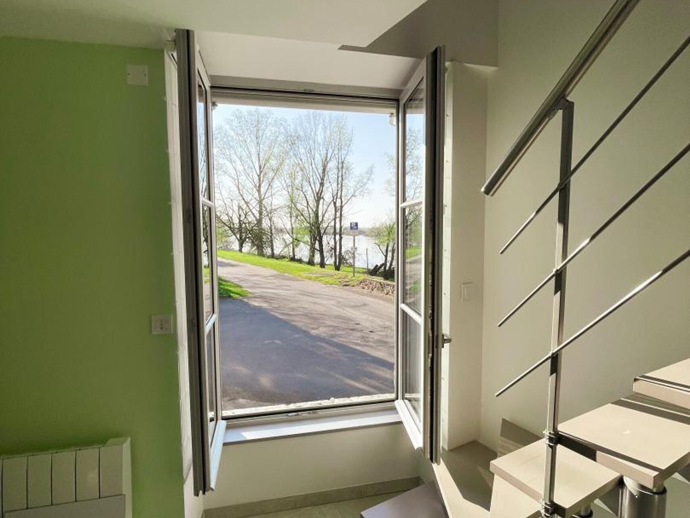 A room with a large window, a staircase, and a radiator.