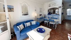 A compact living space with a blue sofa, a dining table, and a kitchen area. - House in Port Grimaud with WiFi and private mooring, near the beach (Port Grimaud)