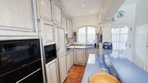 A kitchen with white cabinets, a black oven, a blue countertop, and a woven basket. - House in Port Grimaud with WiFi and private mooring, near the beach (Port Grimaud)