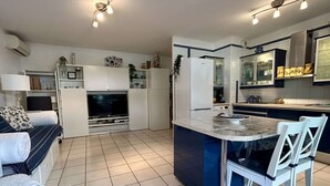 Una cucina moderna con isola centrale, elettrodomestici integrati e zona pranzo con sedie bianche.