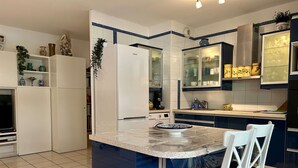 Una cucina con isola centrale, mobili bianchi e forno a microonde.
