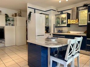 A kitchen with a central island, white cabinets, and a microwave. - Modern apartment with parking and wifi (Balaruc-les-Bains)