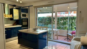 Una cucina moderna con isola centrale, un forno a microonde e un piano cottura. Una porta scorrevole in vetro dà accesso a un balcone con vista sul verde.