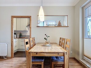 Ein Essbereich mit Holztisch, Stühlen, einer Pendelleuchte und Blick ins Freie durch ein Fenster.