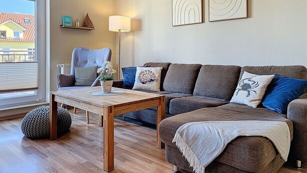 Ein Wohnzimmer mit einer Couch, einem Couchtisch, einer Lampe und Blick durch ein Fenster.