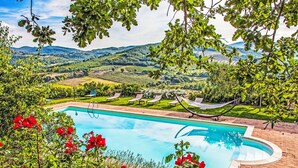 A swimming pool with a view of a vineyard and hills.