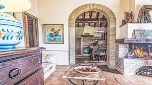 A rustic interior with a fireplace, wooden furniture, and a tiled floor.