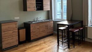 A modern kitchen with wooden cabinets, a built-in oven, and a window with curtains. - Guesthouse LeLo (5) (Solingen)
