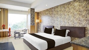 A modern hotel room with a large bed, a desk, a chair, and a view of the outdoors. - Townhouse Oak Ongc Crossway (Dehradun)