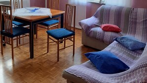 Une pièce comprenant une table à manger, des chaises, un canapé et une fenêtre avec des rideaux.