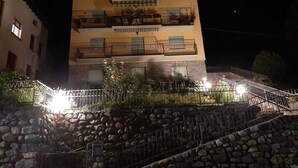 Un immeuble à plusieurs étages doté de balcons, d’un escalier en pierre et d’une rambarde en métal.