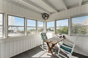 A room with white paneled walls, a wooden ceiling, and large windows offering a view of the beach and ocean. - Ocean Views + Steps to the Beach + 3BDR + King Bed (Oak Island)