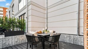 An outdoor patio with a table and chairs, a potted plant, and a brick wall. - Experience Luxury at Ocean's Retreat in Westerland, Sylt (Sylt)