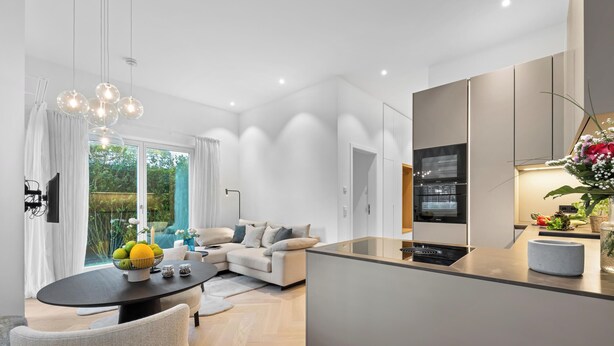 A modern kitchen with a built-in oven, a dining area with a round table, and a sofa. - Experience Luxury at Ocean's Retreat in Westerland, Sylt (Sylt)