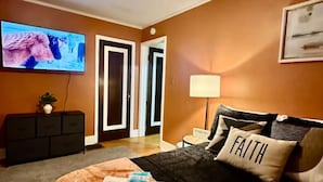 Una habitación de hotel con cama, televisión, escritorio y puerta.