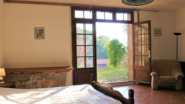 Ein Schlafzimmer mit Bett, Stuhl, Fenster und einer Tür, die nach draußen führt.
