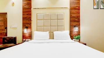 Een hotelkamer met een groot bed, houten paneelwanden en een modern hoofdeinde.