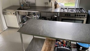 A modern kitchen with stainless steel appliances, a dishwasher, a sink, and a window providing a view of the outdoors. - 4 Star Holiday Home in Orsted (Ørsted)