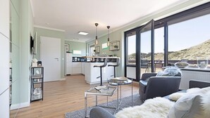 Una sala de estar moderna con un sofá, una mesa de centro y un comedor con vistas al exterior.